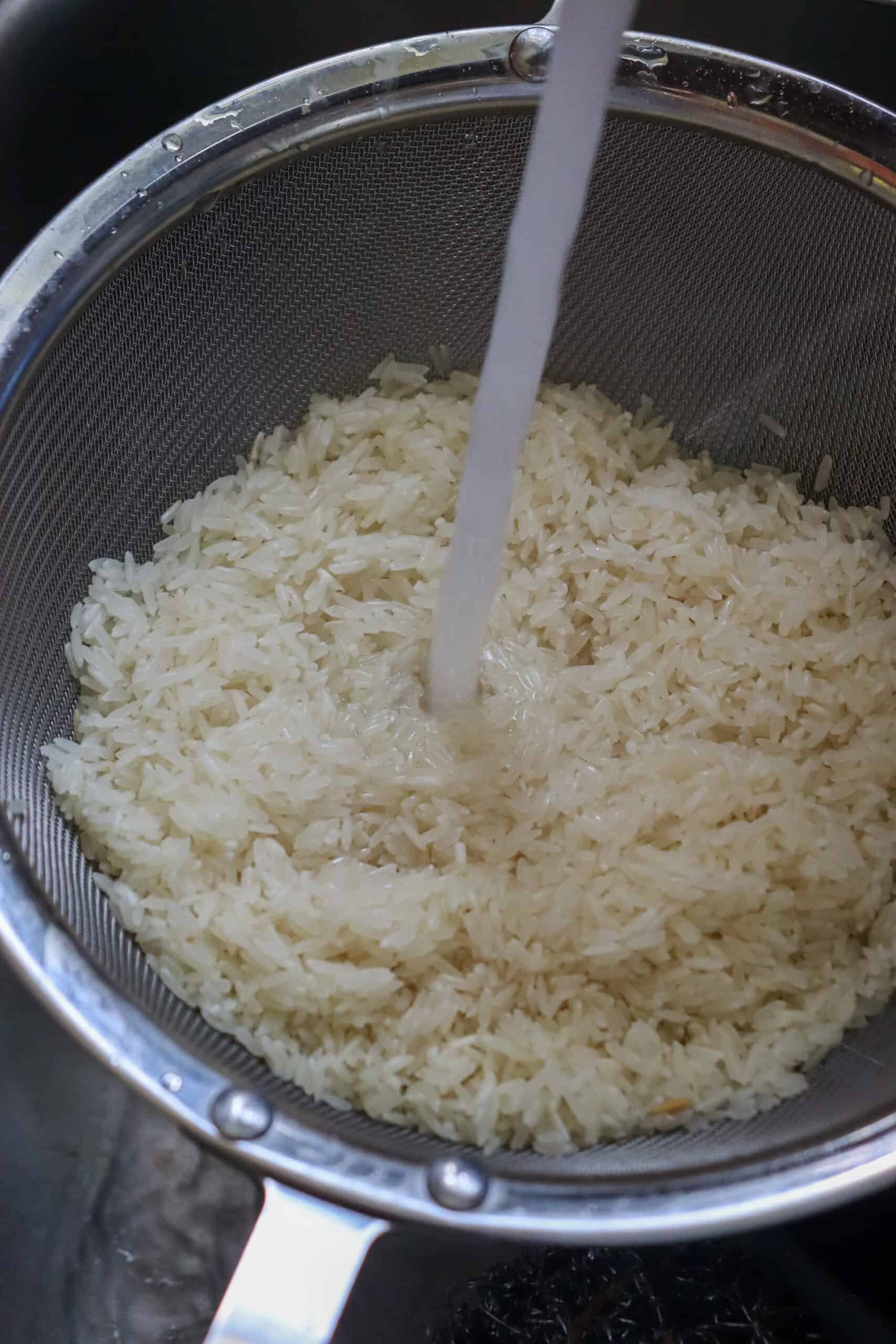 water running through rice in a strainer